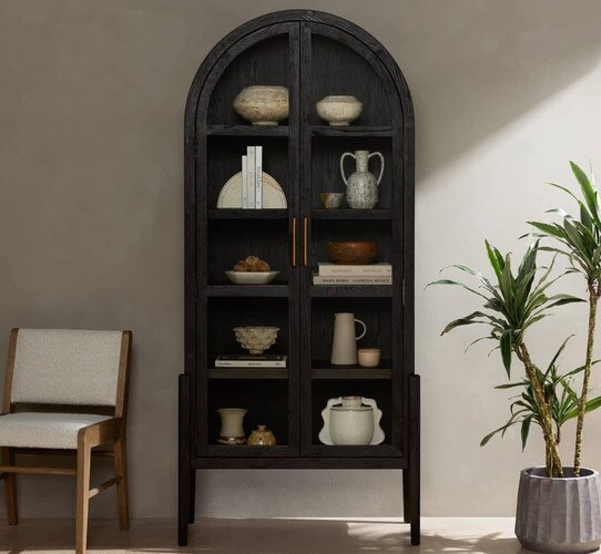 Blue arched bookshelf holding books and ceramics