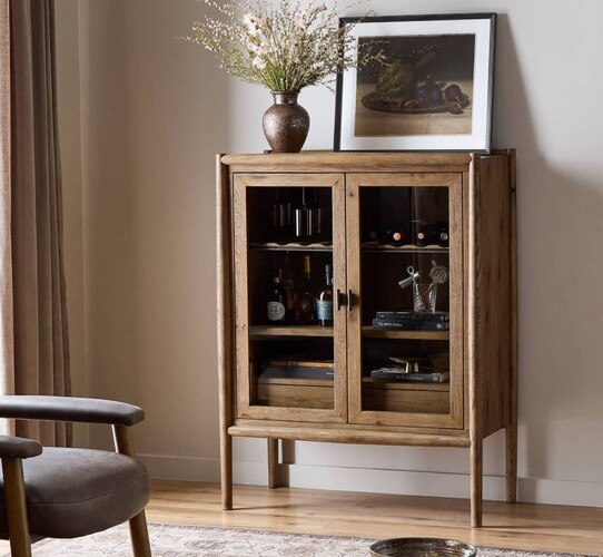 Bar cabinet with glass front holing bottles of liquor and books