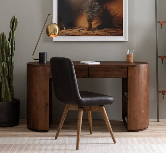 Wood office desk with a black leather chair and brass task lamp