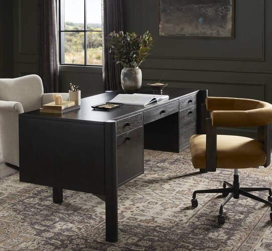 Black wood desk in front of a mustard colored chair