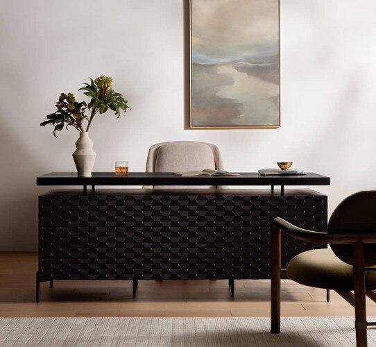 Black desk under a landscape painting of a river