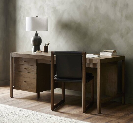 Wood desk with side drawers holding paper and a black table lamp