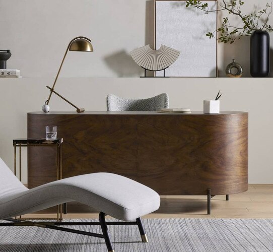 Oval wood desk holding a brass table lamp