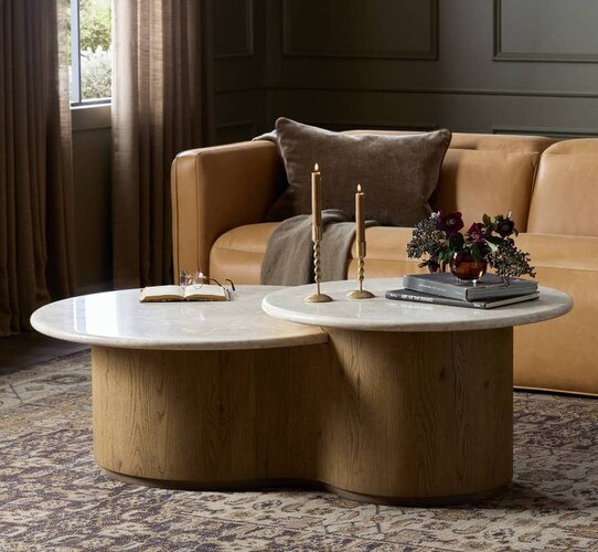 Wood and marble two tiered coffee table holding candle sticks and an open book