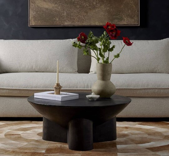 Small black circular coffee table holding a ceramic vase with red flowers
