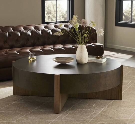 Black and wood circular coffee table in front of a brown leather sofa