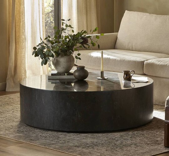 Circular black marble coffee table in front of white sofa