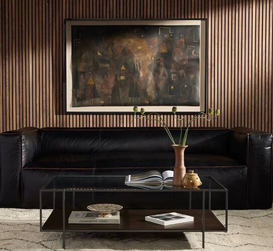 Black leather sofa with a metal and glass coffee table in front of it