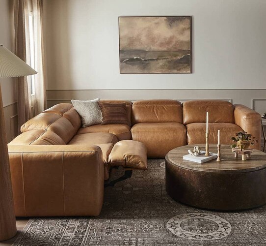 Leather sectional with marble circular coffee table beside it