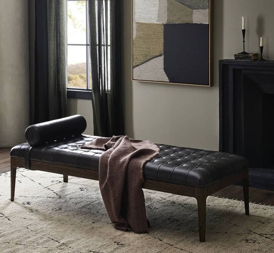 Black leather day bed with a blanket draped over it