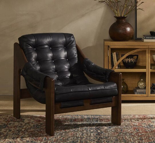 Black leather and wood chair beside a glass front credenza