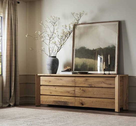 Wood dresser holding large painting of a green landscape and vases