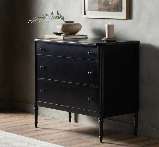 Tall three drawer black dresser with a candle on top