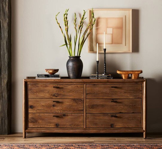 Six drawer wood dresser holding a large vase and candlesticks