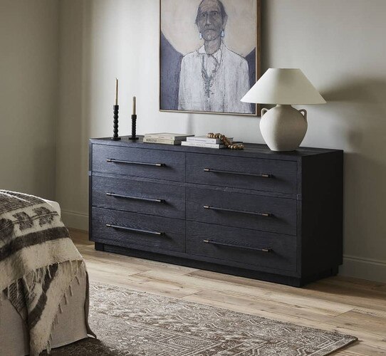 Black and brass dresser under a painting of a native american