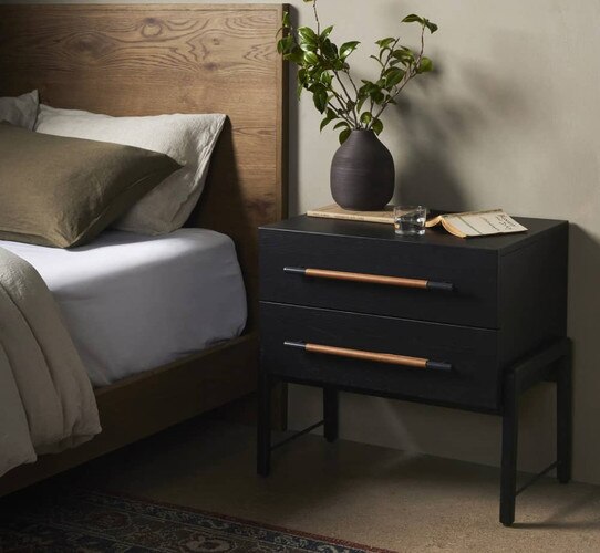 Black and wood tone nightstand beside a wood bed