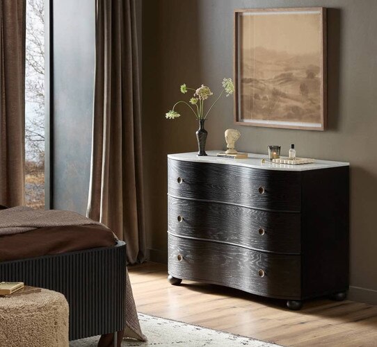 Curved wooden dresser with a white marble top under a painting