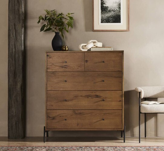 Five drawer wood dresser with a black vase on top of it