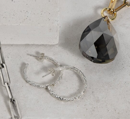 Gold necklace beside silver earrings