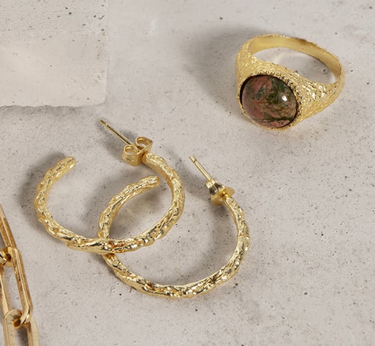 Gold earrings and a gold ring with unakite on a table