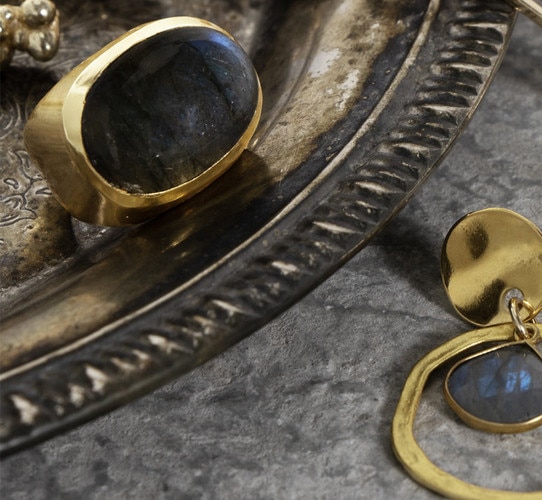 Patinaed plate holding a gold ring with large labradorite stone