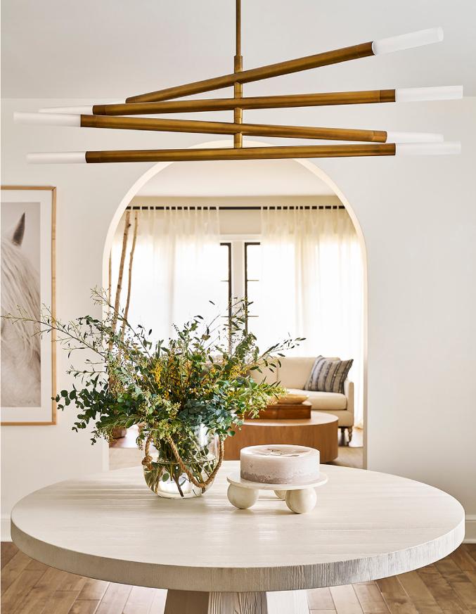 natural brass chandelier above circular table with flowers on top