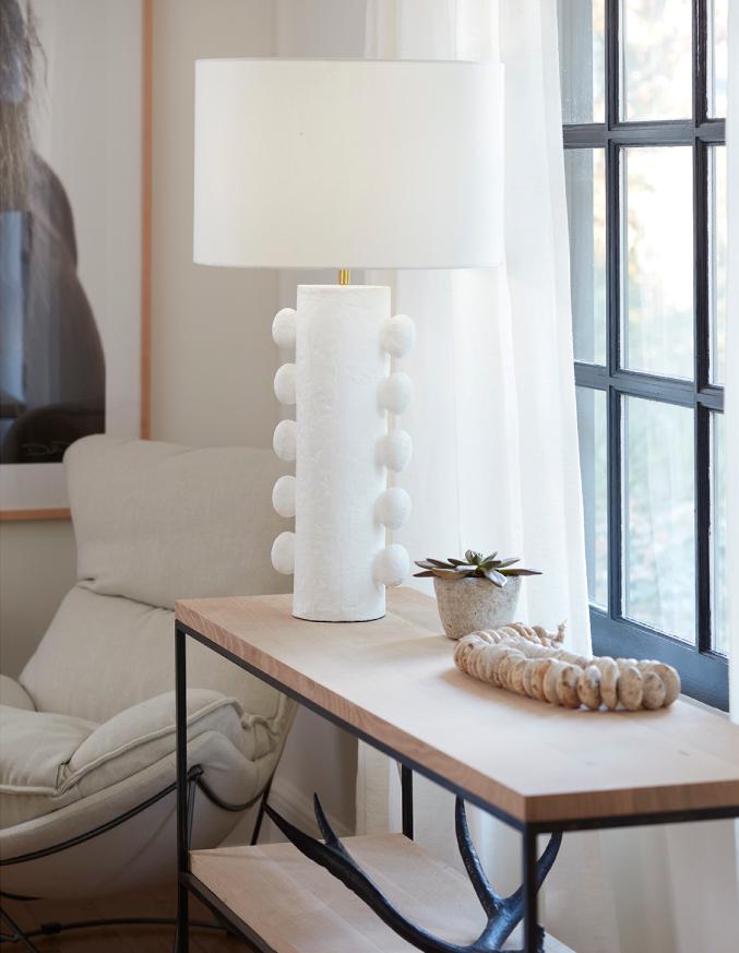 White table lamp on a wooden console table near a window