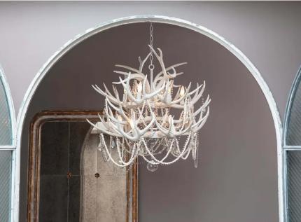 White antler chandelier in front of gray wall