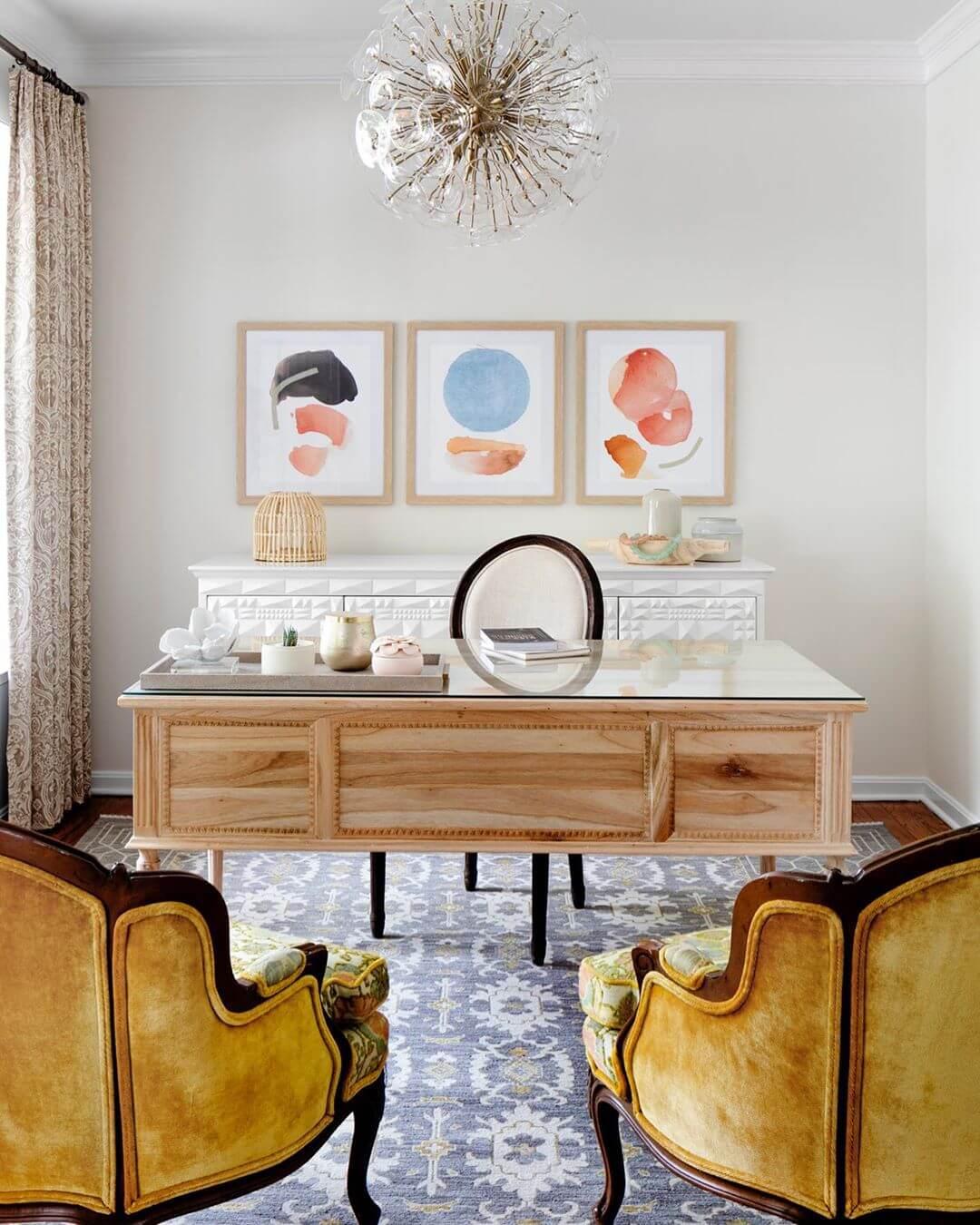 Home office with a blue carpet, wood desk, vintage chairs, and a glass chandelier