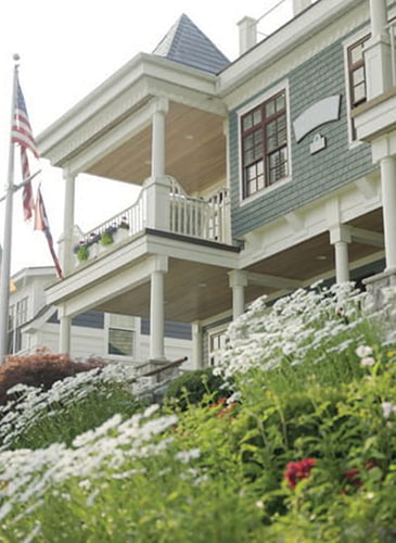 Green colored home with wildflowers and the flag of USA