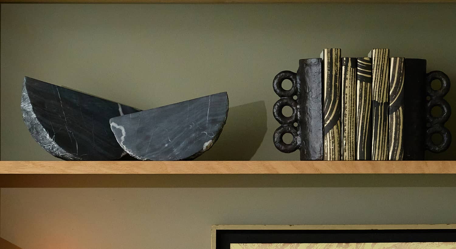 Shelf with black and gold books beside a marble sculpture