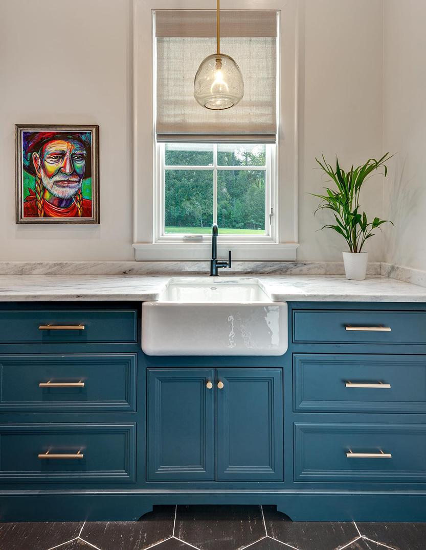 Bathroom counter with blue cabinet doors and molten glass pendant with natural brass fittings