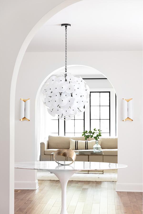 Entryway with a marble topped circle table and a white and black poppy inspired chandelier with black chain