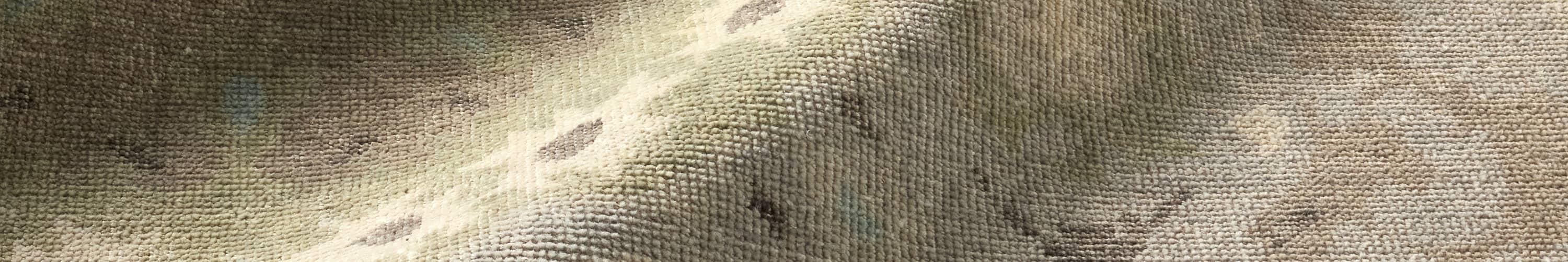 Handwoven rug below a green sofa