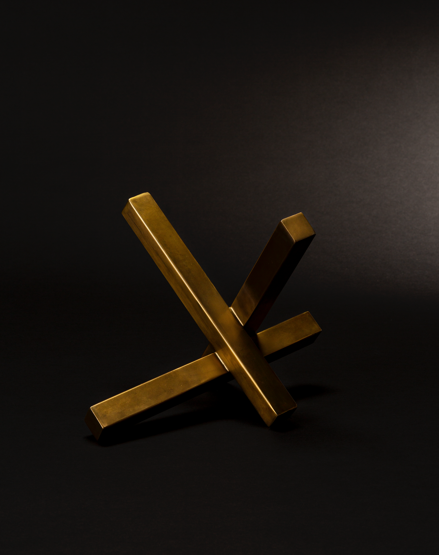 Intersecting natural brass sculpture on a black background