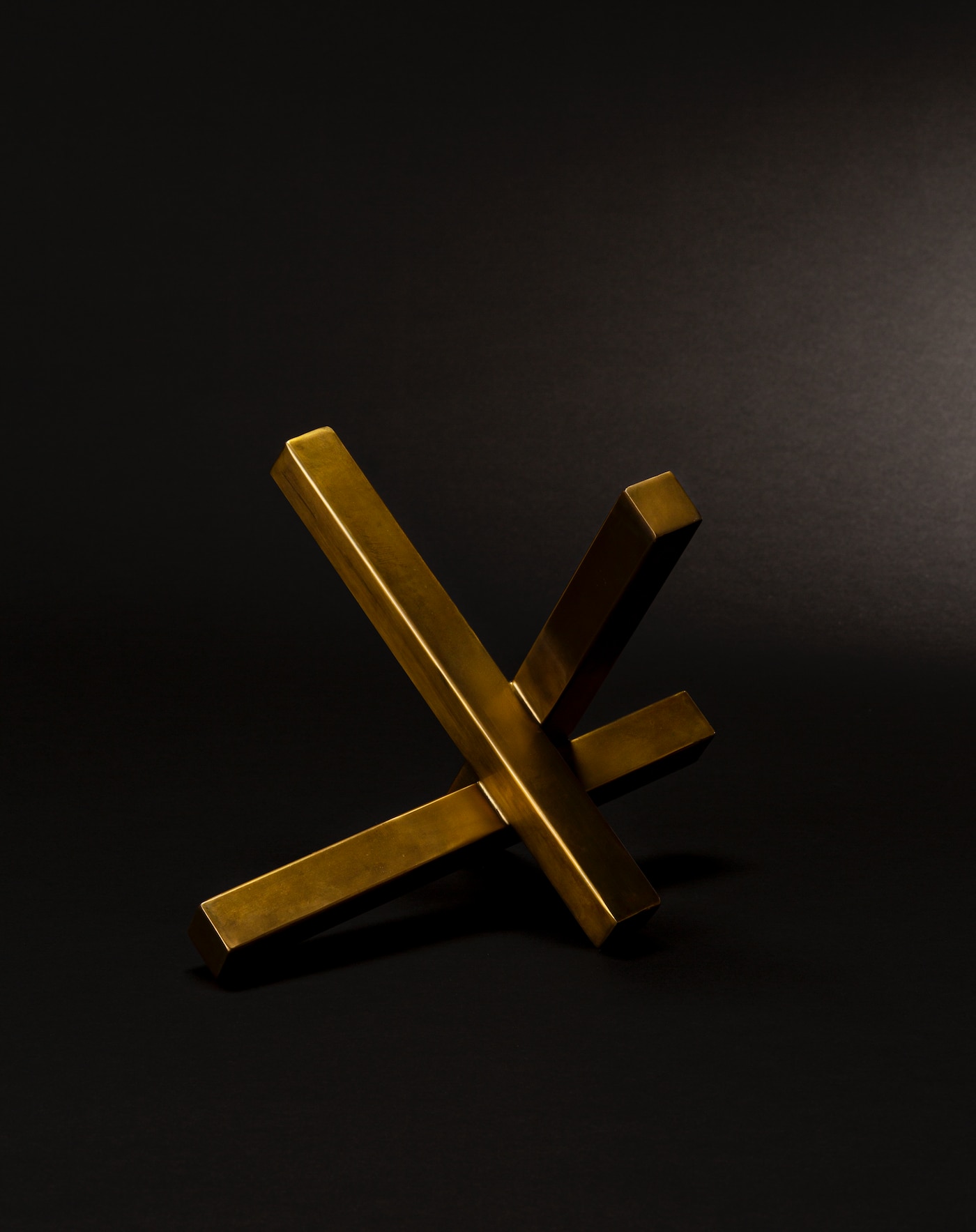 Intersecting natural brass sculpture on a black background