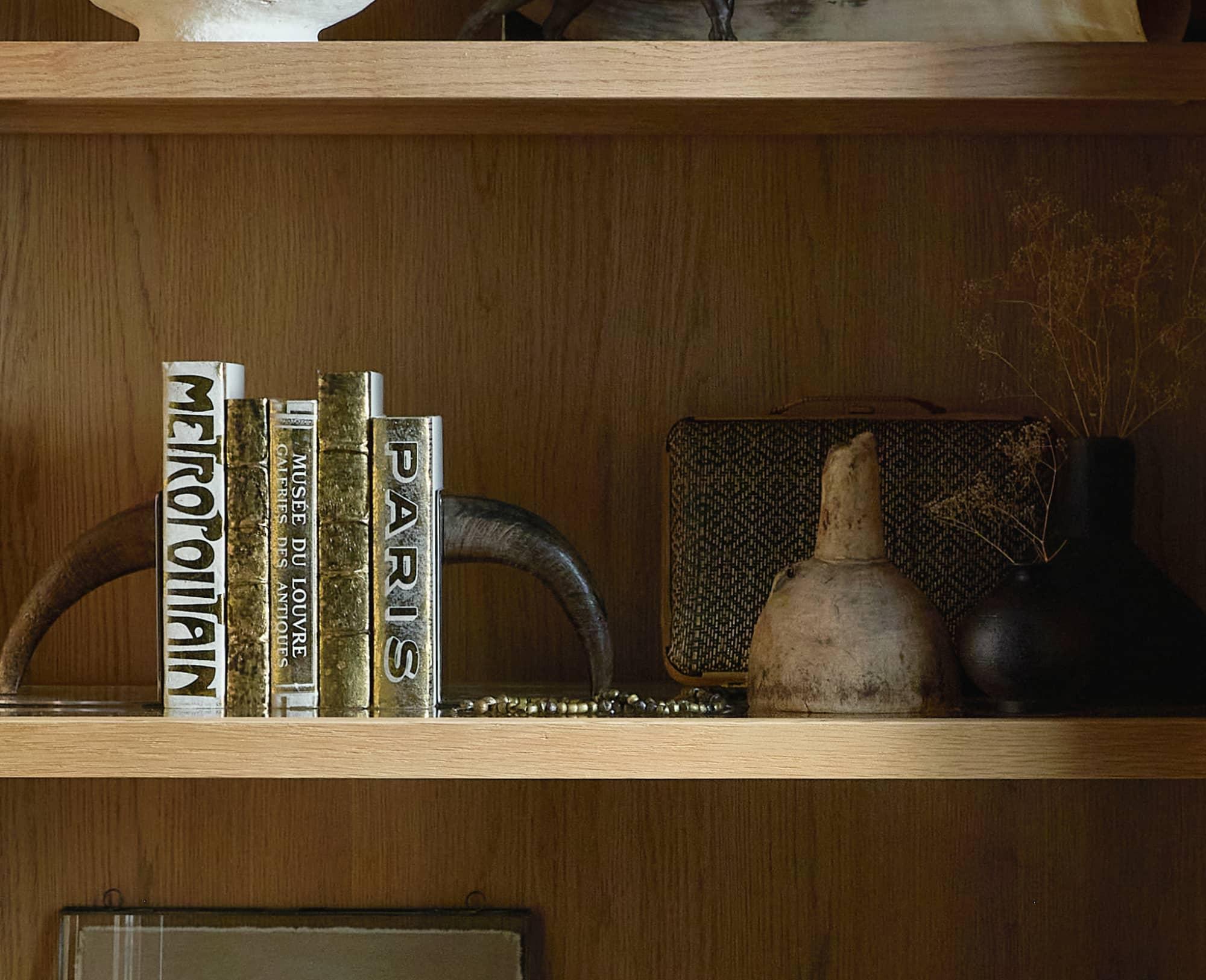 Shelf holding textured hardcover books and a ceramic vase