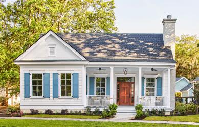 Southern home with blue shutters, a green lawn, and a red door